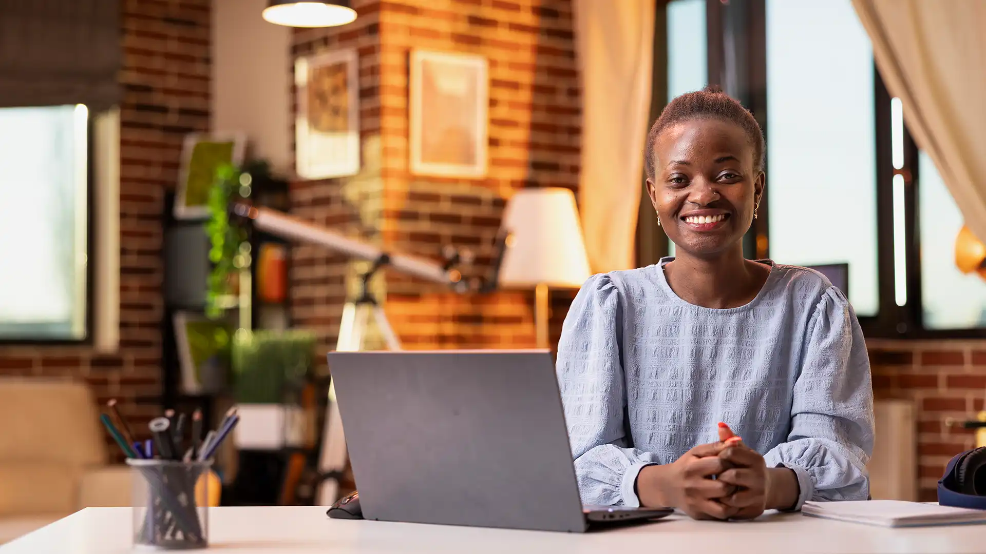 Independent professional smiling at her laptop in a creative workspace